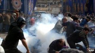 A policeman uses a baton against demonstrators fleeing in a cloud of tear gas in Alexandria. Photo: 28 January 2011