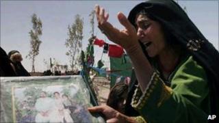 An Afghan woman mourns as she holds a poster with photos of her family members killed during a US-led raid in Herat province in Afghanistan in 2008