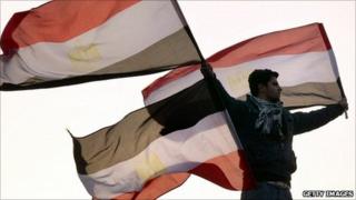 A protester in Tahrir Square holds Egyptian flags - 1 February 2011