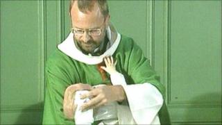 A vicar christening a baby