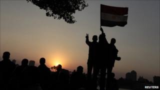 Солнце садится на протестующих во время демонстрации на площади Тахрир в Каире 11 февраля 2011 года. A