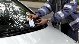 A civil enforcement officer issuing a parking ticket in