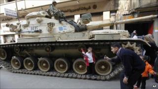 A man photographs his daughter on an Egyptian army tank, in Tahrir Square - 14 February 2011