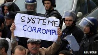 An anti-government protesters holds a sign on which reads "Corrupted system" during a demonstration in Algiers on 19 February 2011.