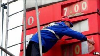 A worker changes the price signboard at a petrol station in central China