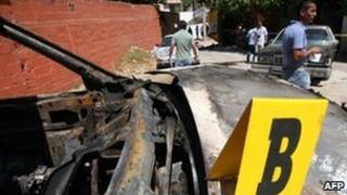 People stand near a burnt vehicle in Acapulco, 20 February