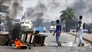 UN peacekeepers drive past supporters of Alassane Ouattara as they demonstrate in Abidjan on 19 February 2011