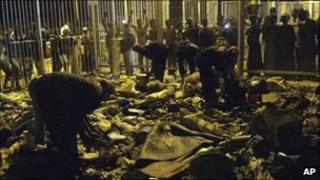 People look on as security guards clean up personal belongings and debris following a deadly stampede at Modibo Keita Stadium in Bamako, Mali, 21 February 2011