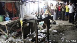 Bystanders look on after a blast in Rangoon, Burma, 27 February 2011