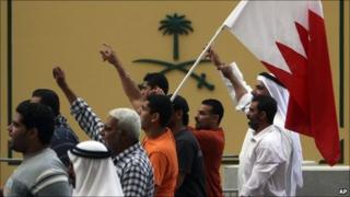 Bahraini anti-government protesters wave the national flag as they march past the embassy of Saudi Arabia in the capital Manama, 27 February 2011