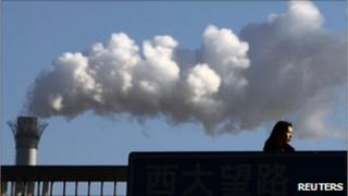 Файл с изображением женщины, проходящей мимо угольной электростанции в Пекине 25 февраля 2011 года