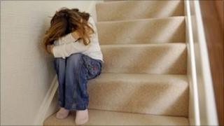 Child on stairs hiding head in hands