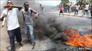 Anti-Gbagbo protesters stand near a roadblock and burning tyres in the Abobo area of Abidjan 3 March 2011