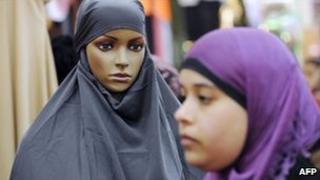 A woman in a headscarf passes a dummy covered with a veil at a stand during a meeting of French Muslims in Le Bourget, outside Paris, April 2010