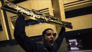 A protester holds up a sign from the State Security Investigation Service (SSIS) headquarters in Nasser City, Cairo