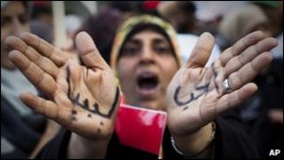 A Libyan woman reacts with her hands written on them in Arabic " I love Libya"