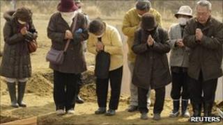 Mourners at a temporary mass grave in Miyagi prefecture, northern Japan, 25 March 2011