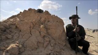 Libyan rebel takes cover as they try to retake the town of Ajdabiya