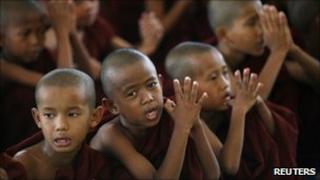 Novice Buddhist monks pray in front of the reclining Shwethalyaung Buddha statue in Bago, about 100km (60 miles) north of Rangoon