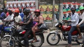 Motor cyclists wait at a traffic stop in front of election campaign posters in Yaba, Lagos, Nigeria, Wednesday 30 March 2011