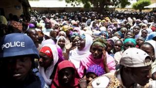 A police officer in riot gear (L) guards a crowded polling station in Kano, northern Nigeria, April 9, 2011.