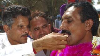 Released Indian national Gopal Das wearing garlands receives sweets from his relative after crossing into India
