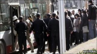 Chinese police usher people onto a bus at the site of a planned outdoor service by the Shouwang Church at the Zhongguancun commercial district in Beijing (10 April)