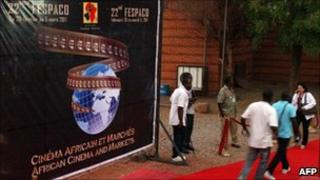 Посетители проходят мимо официального плаката 22-го Fespaco, крупнейшего в Африке кинофестиваля