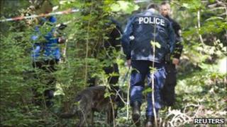 A Zurich policeman walks through the forest with his sniffer dog in Tolochenaz near Morges April 14 , 2011, after Vaud Police organised a search operation from Morges to St-Prex.