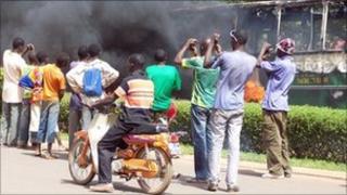 Residents take pictures of a bus burning during a demonstration in Ouagadougou on 16 April 2011