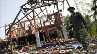 A Thai man walks past a destroyed house in Karb Cherng village in Surin province on 27 April 2011