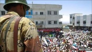 A Yemeni soldier watches anti-government protesters in the city of Taiz, 30 April