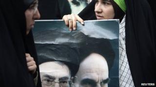 An Iranian student holds a poster with pictures of Iran's late Leader Ayatollah Ruhollah Khomeini (R) and Supreme Leader Ayatollah Ali Khamenei during a demonstration in support of the anti-government protests in Bahrain outside the Bahrain embassy in Tehran on 30 April 2011