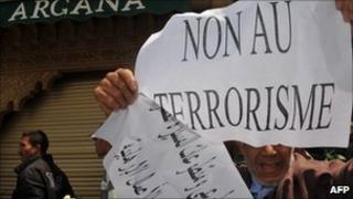 A man holds a sign in front of the Argana Cafe in Marrakesh during a demonstration (7 May 2011)