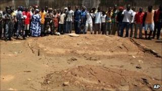 Residents look on as soldiers visit the site of an alleged mass grave in Yopougon district, Abidjan, on 5 May 2011
