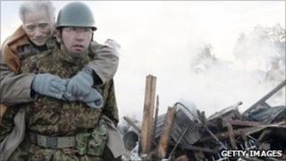 A soldier carries a elderly man to a shelter