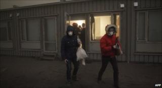 Tourists in face masks leave a hotel near the erupting volcano