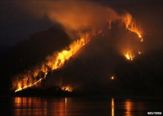 A wildfire burns through woods on a bank of the Yenisei river near Krasnoyarsk, Russia, 21 April