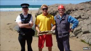 RNLI lifeguard Cameron Coulson, Police Officer Ben De La Haye, and Explosive Technician Stuart Elliott with the detonated device