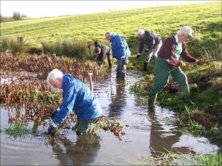 Voluntary wardens at work clearing a pond in the Cotswolds