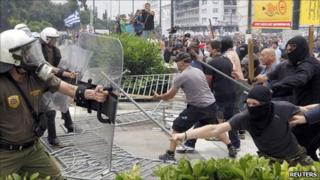 Masked demonstrators and riot police clash near the Greek parliament in Athens on 15 June 2011