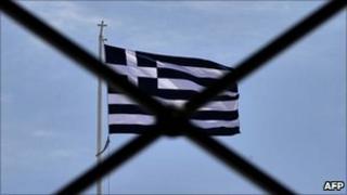 Greek national flag waves behind rails above the parliament in Athens
