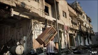 A Libyan youth carries away a piece of furniture from a destroyed building in Tripoli street