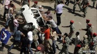 Protesters overturn a police car in front of the courthouse in Suez, 6 July