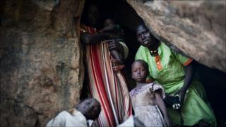 A terrified mother looks out of a cave as she takes shelter from an aircraft flying over the hills surrounding Lwere in Sudan's Nuba mountains on 1 July as hundreds of families have fled their villages in South Kordofan following recent bombing by the Sudanese armed forces