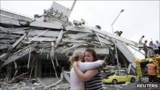 Две женщины обнимают друг друга перед обрушившимся зданием в центральной части Крайстчерча 22 февраля 2011 года