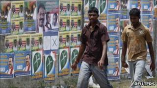 Two men walk past local government election campaign posters in Jaffna, Sri Lanka, on Friday