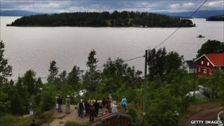 People lay flowers at Tyrifjorden Lake next to Utoeya island on 25 July 2011