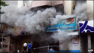Fire fighters work to extinguish a fire in a shop torched during a fresh wave of violence in Karachi