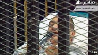 Mubarak appeared on a stretcher inside the defendants' cage